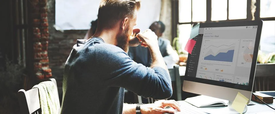 A man sitting at his work desk drinking coffee.