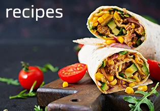 Tacos on a wooden board with tomatoes on the side.