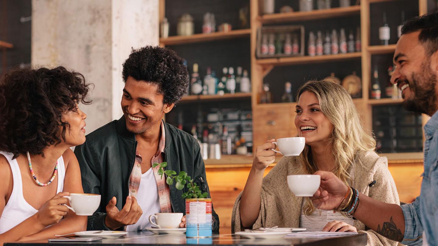 2 women and 2 men chatting over coffee.